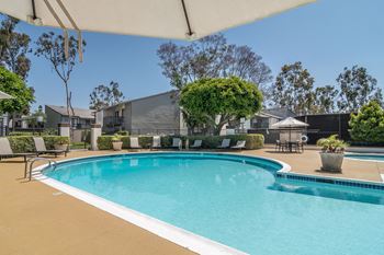 a swimming pool with chairs around it and buildings in the background